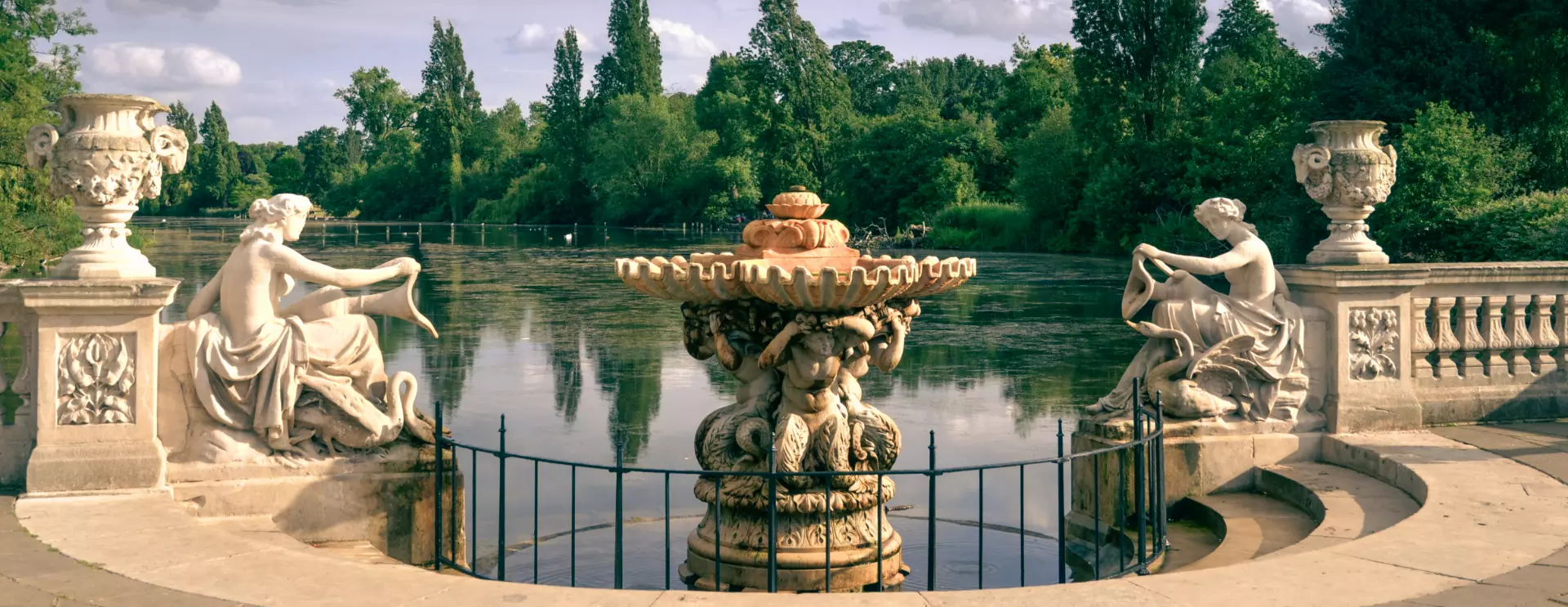 A beautiful scene of the Italian Gardens in Hyde Park, featuring lush greenery, serene water features, and classical sculptures.