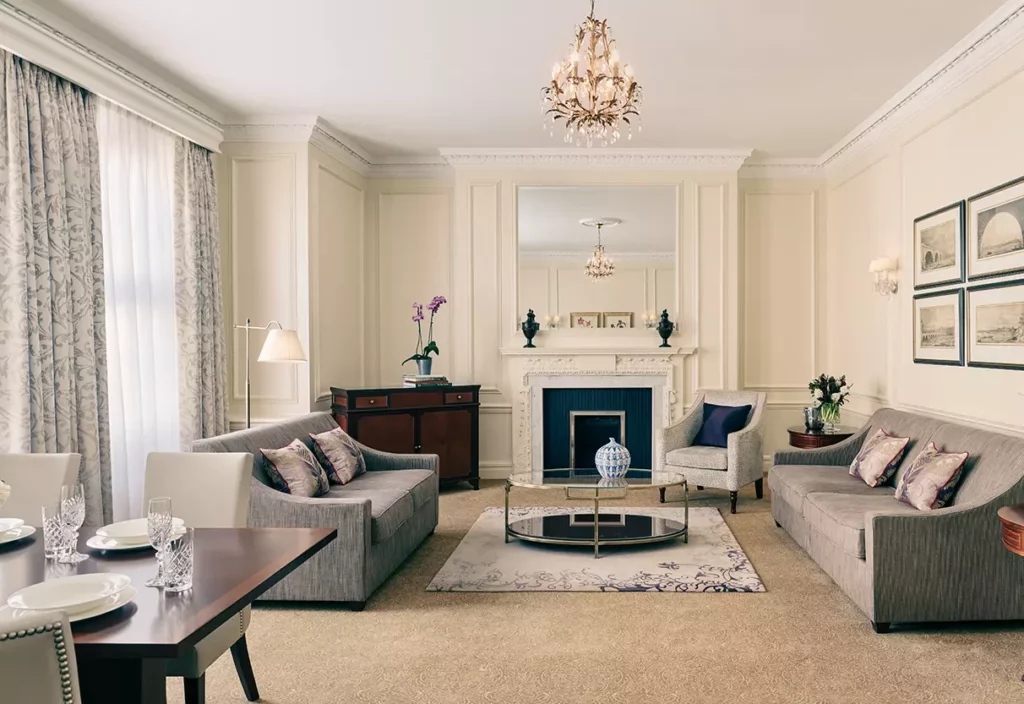 Large living room with grey sofas, area rug and coffee table, dining table, armchairs, window treatments and art on walls