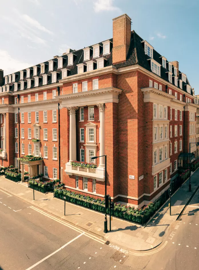 Outside view of 47 Park Street in London, England, with red brick façade white window trim, and well-manicured greenery